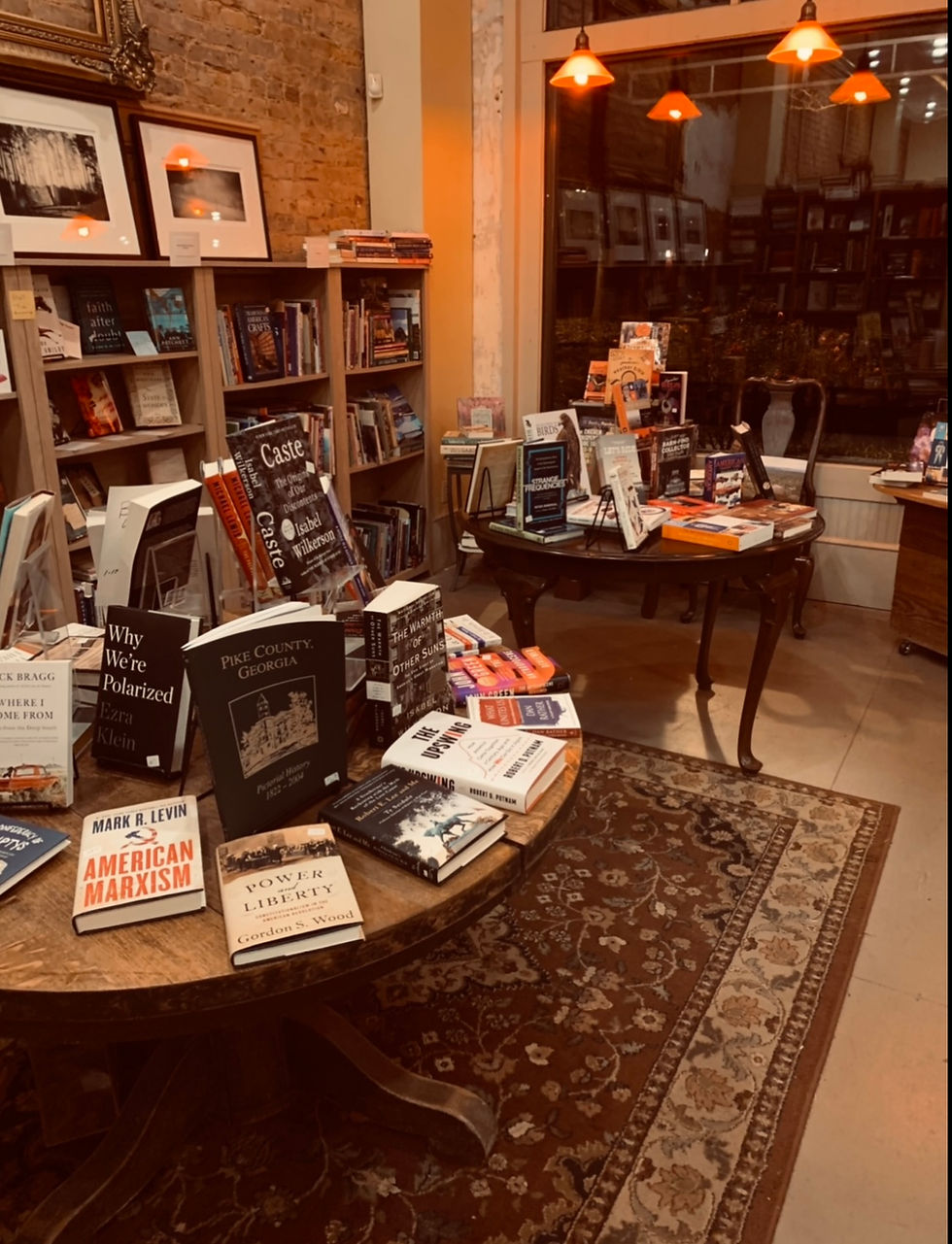 Warmly lit bookshelves and display tables inside A Novel Experience in Zebulon.