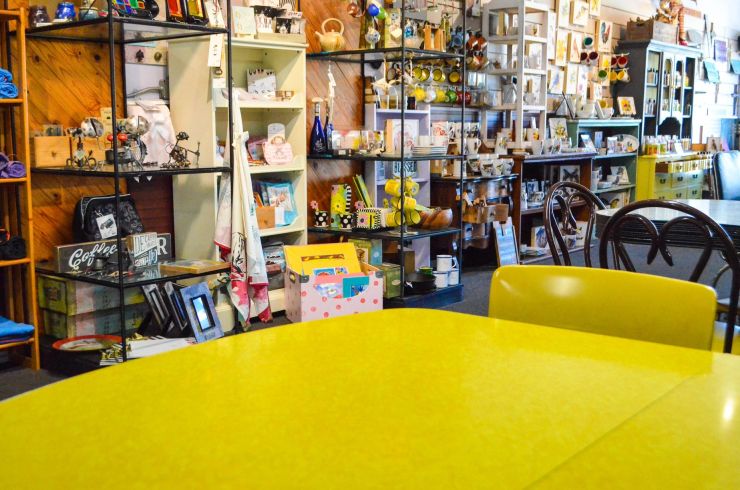 Yellow café table in front of art, craft and gift displays inside UniquExpressions.