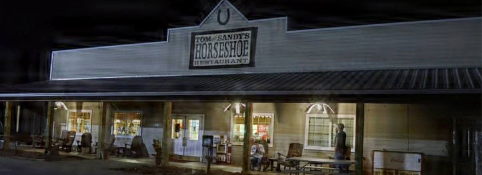 Tom and Sandy's Horseshoe Restaurant exterior with a covered porch and illuminated windows.