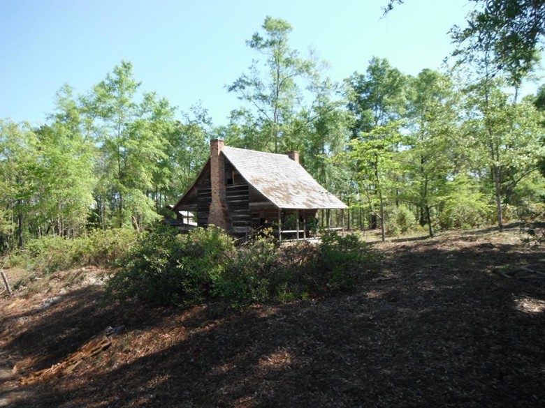 Historic log house among pine trees at the Brewton-Parker campus village.
