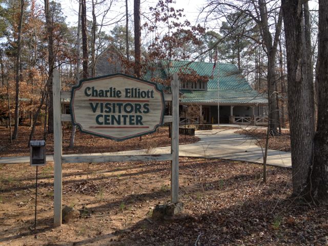 Charlie Elliott Wildlife Center sign and visitor-center building among trees.