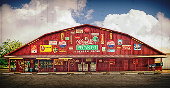 Red Merritt Pecan Company country-store facade covered with vintage advertising signs.