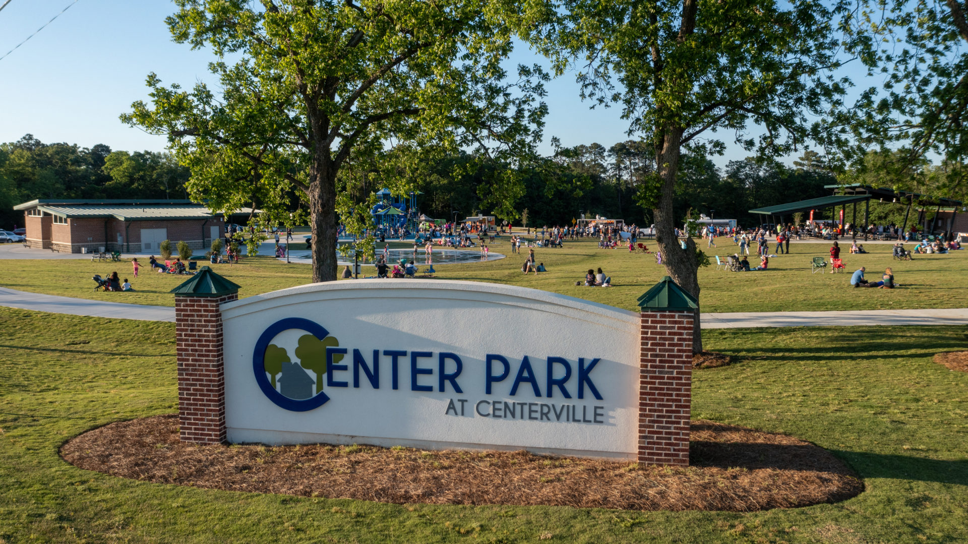 Center Park at Centerville entrance sign, lawn, playground and pavilion during a community gathering.