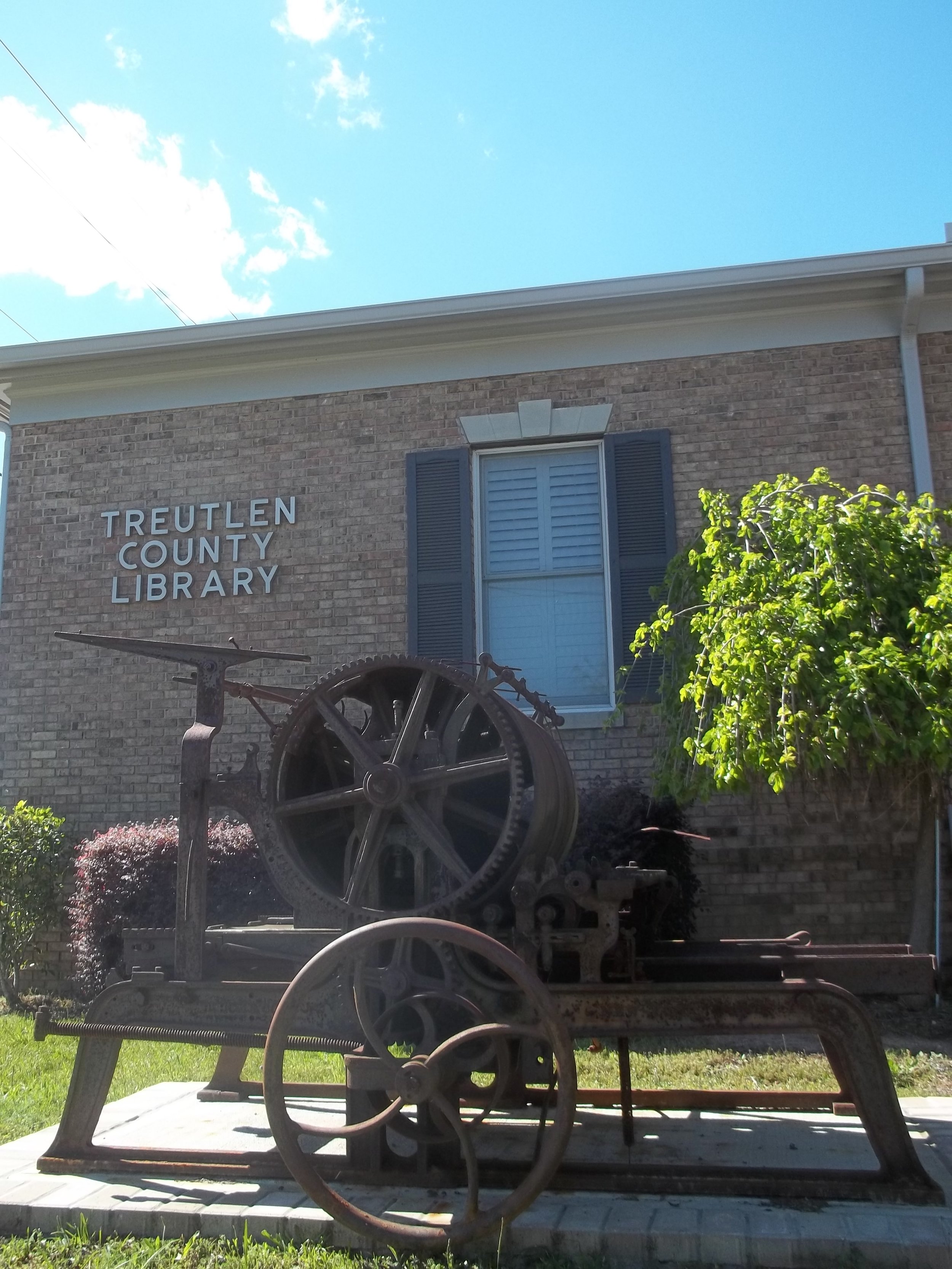 Treutlen County Library's labeled brick building with a historic machine displayed outside.