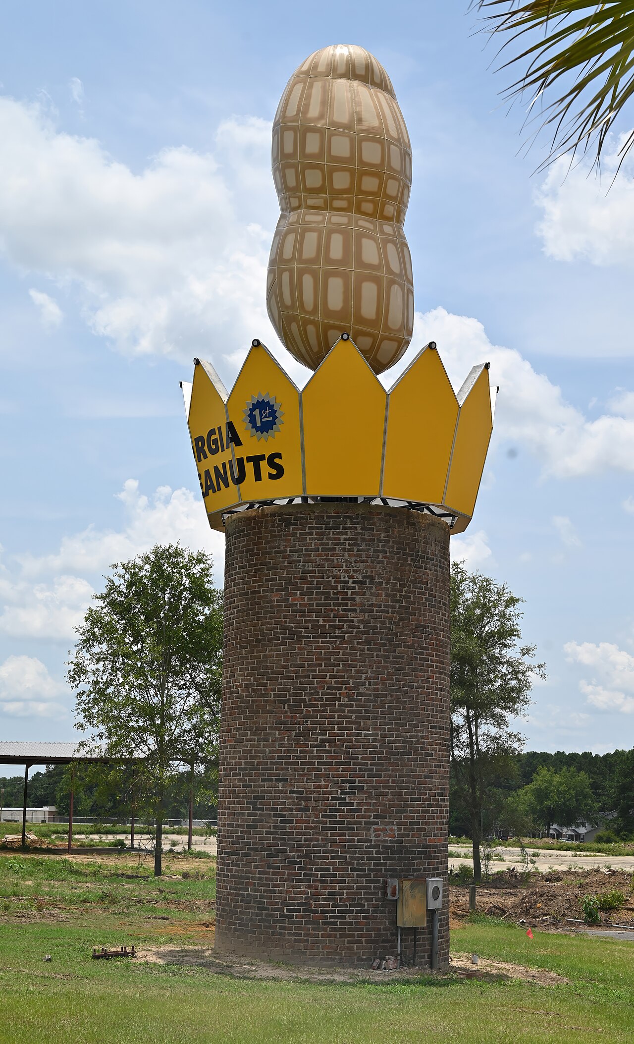 Ashburn's tall metal peanut and crown on a brick pedestal under a blue sky.
