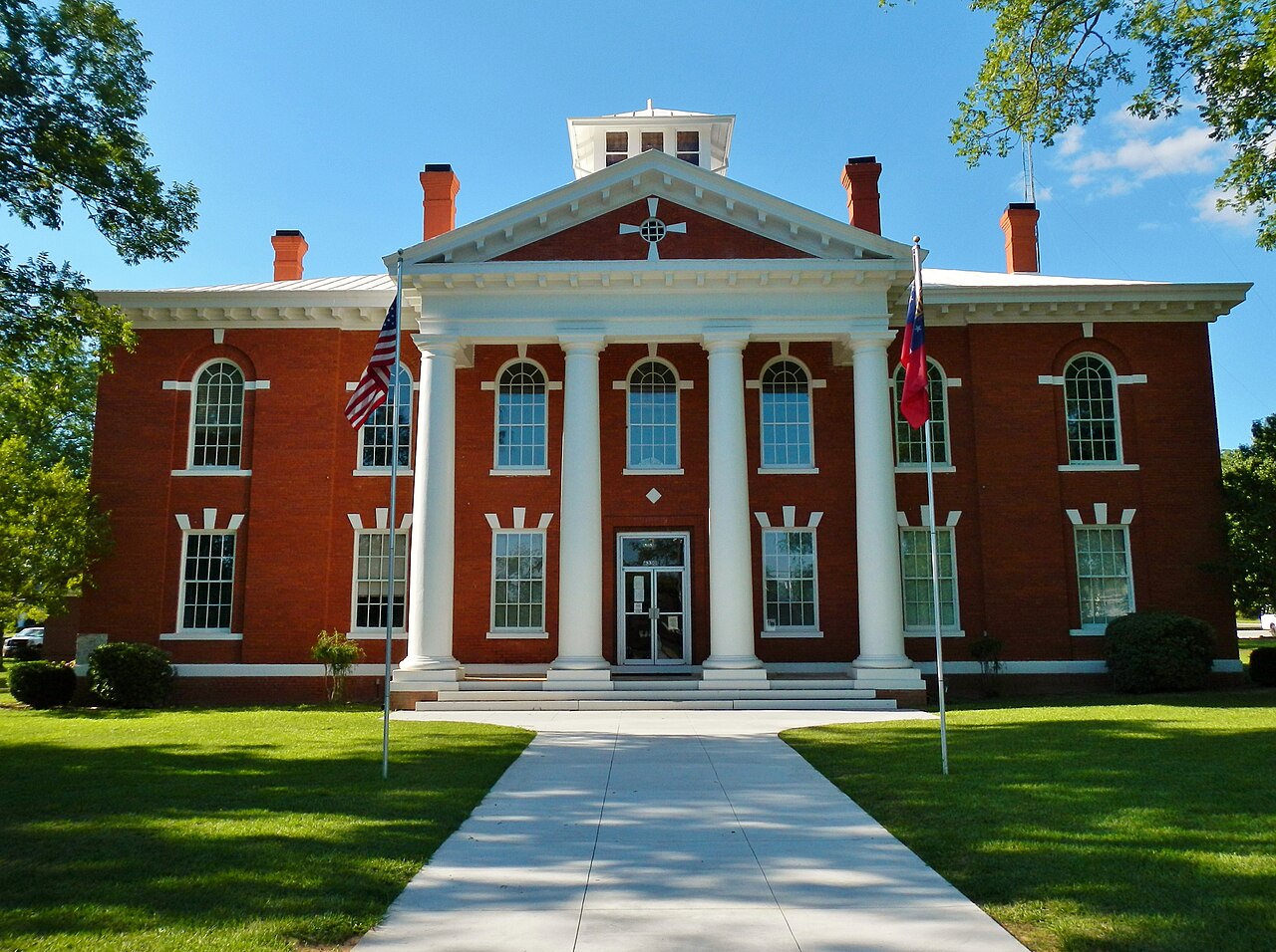 Webster County Courthouse's red-brick facade, white columns, cupola, flags and lawn in Preston.