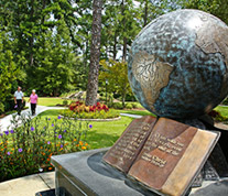 Flowers, a path and the globe-and-open-book scripture monument at Guido Gardens.