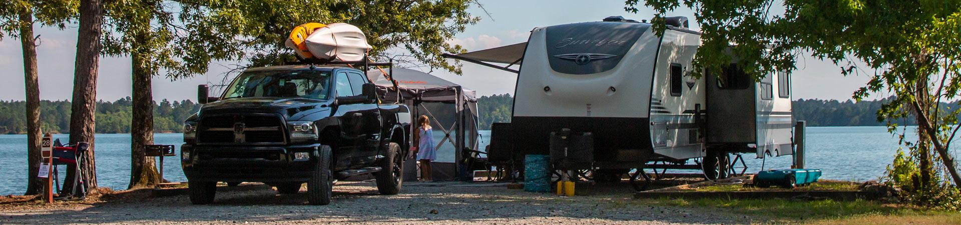 A waterfront campsite with an RV, truck and kayaks beside Lake Juliette at Dames Ferry.