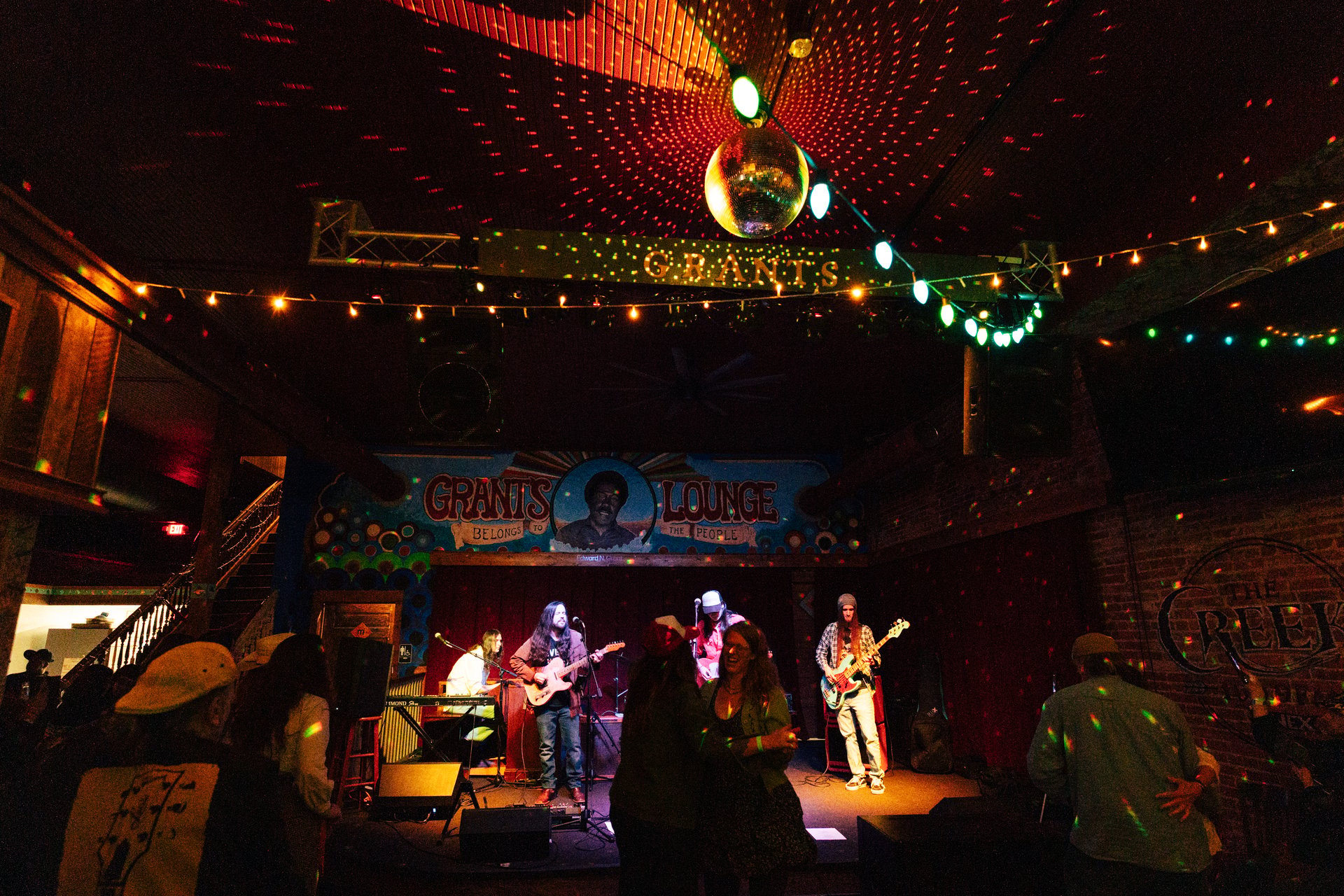 A band performing under the Grant's Lounge mural before a standing crowd in Macon.