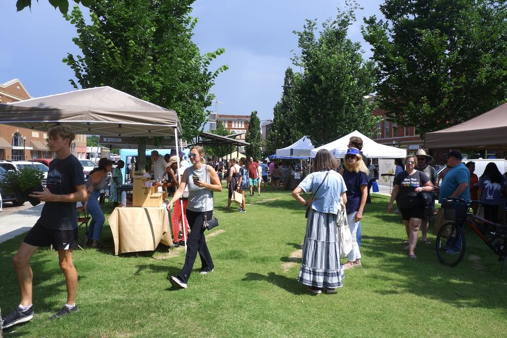 Shoppers visiting produce and farm tents at the Poplar Street farmers market in downtown Macon.