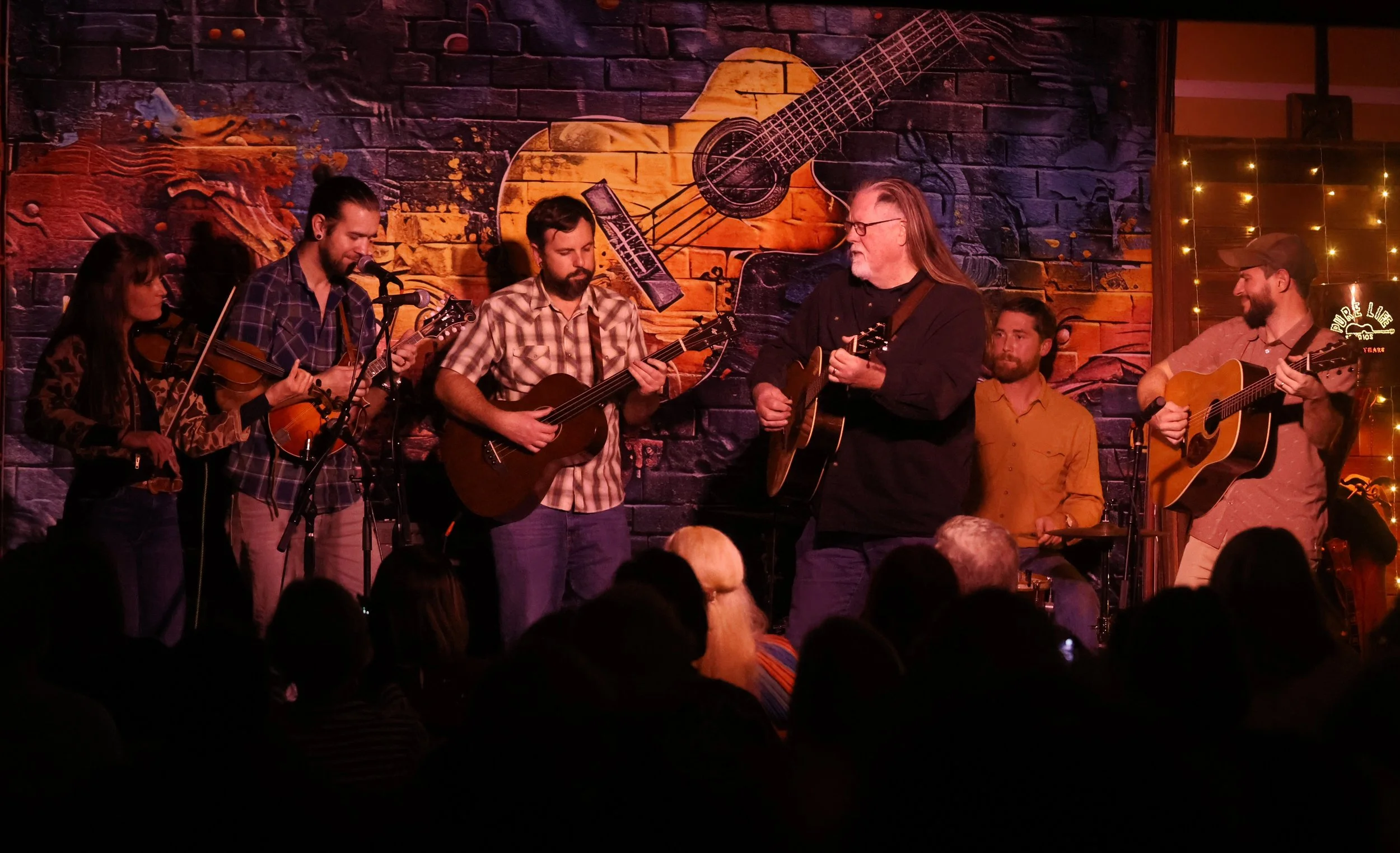 An acoustic group performing before a seated audience inside Pure Life House of Music.