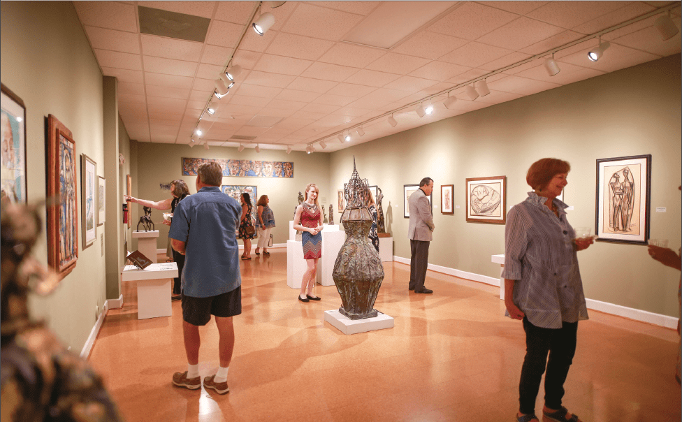 Visitors viewing sculpture and framed artworks inside the Steffen Thomas Museum of Art.