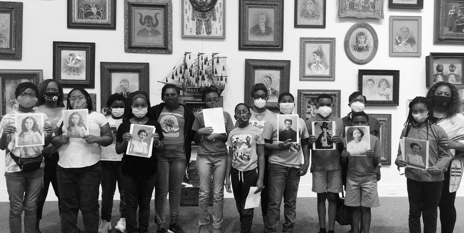 Students holding historical portrait references inside a gallery at the Albany Museum of Art.
