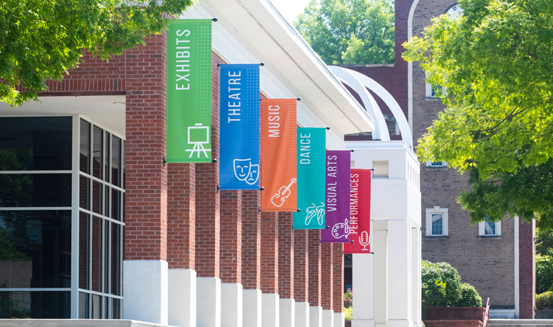 The brick Carrollton Center for the Arts with banners naming its music, dance, theater and visual-arts programs.