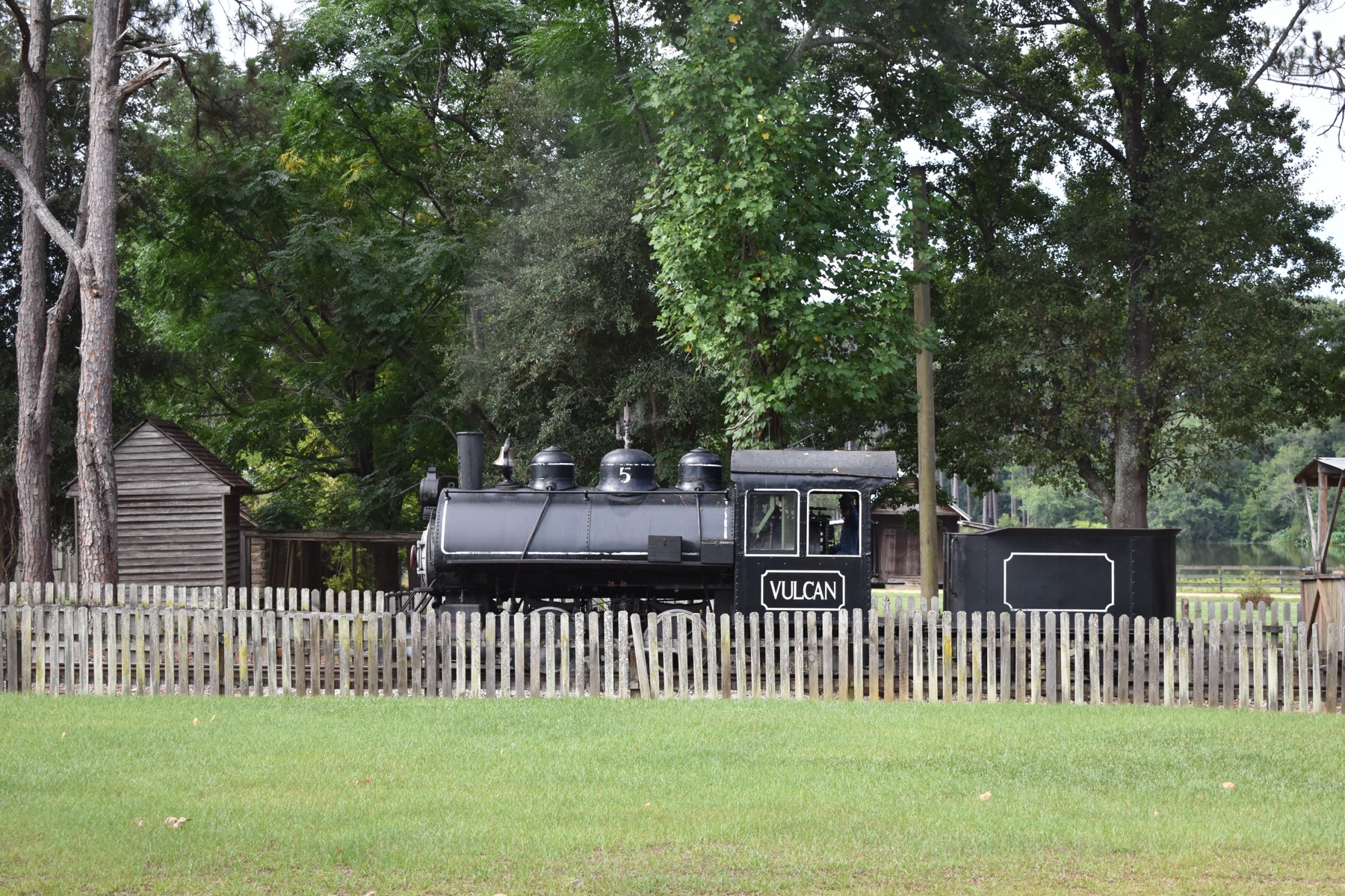The black Vulcan No. 5 locomotive behind a picket fence in the Georgia Museum of Agriculture historic village.