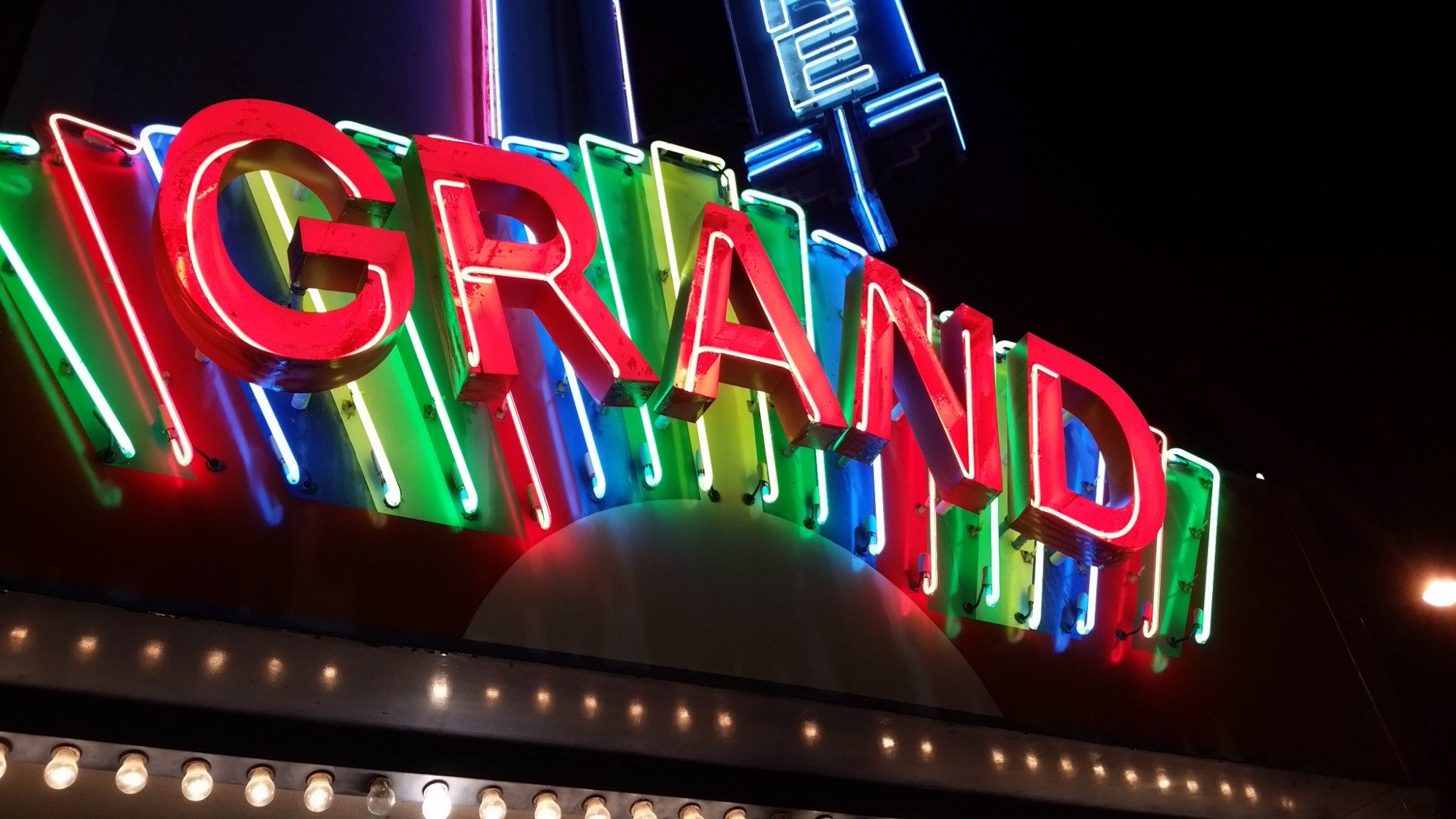 The restored Grand Theatre neon marquee glowing at night in downtown Fitzgerald.