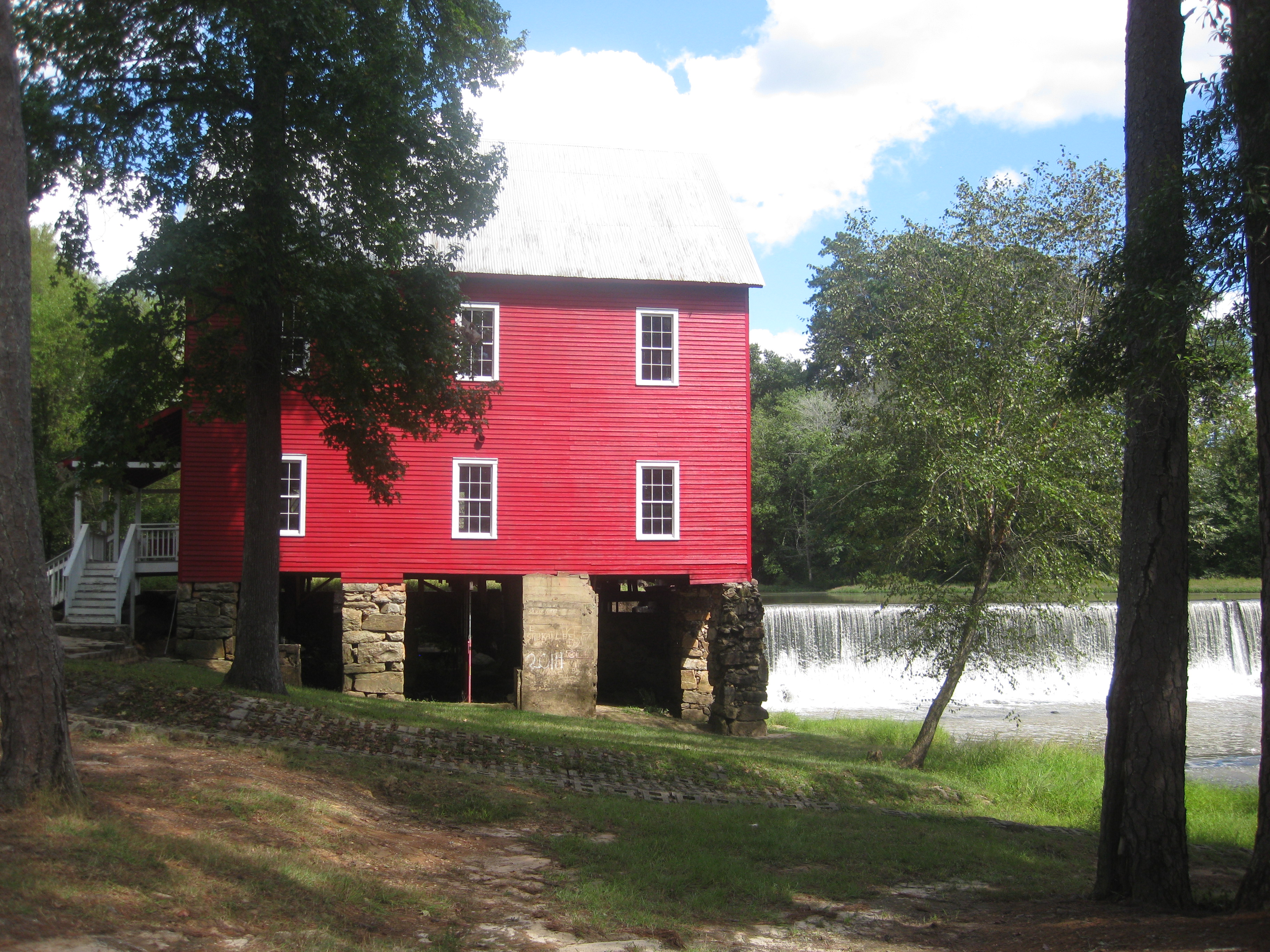The bright red Starr's Mill building beside its stone dam and broad waterfall.