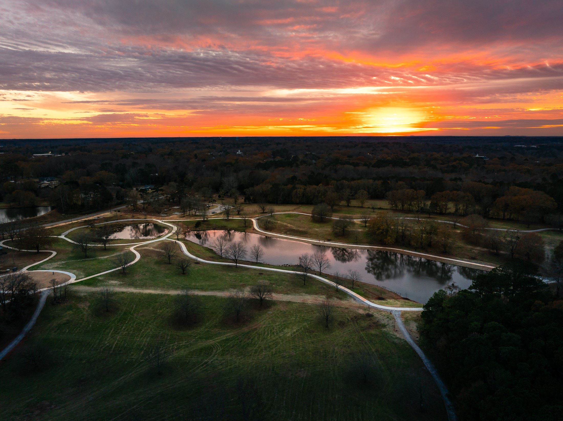 Aerial sunset view of ponds, pasture and looping paved paths at Thomas Farm Preserve.