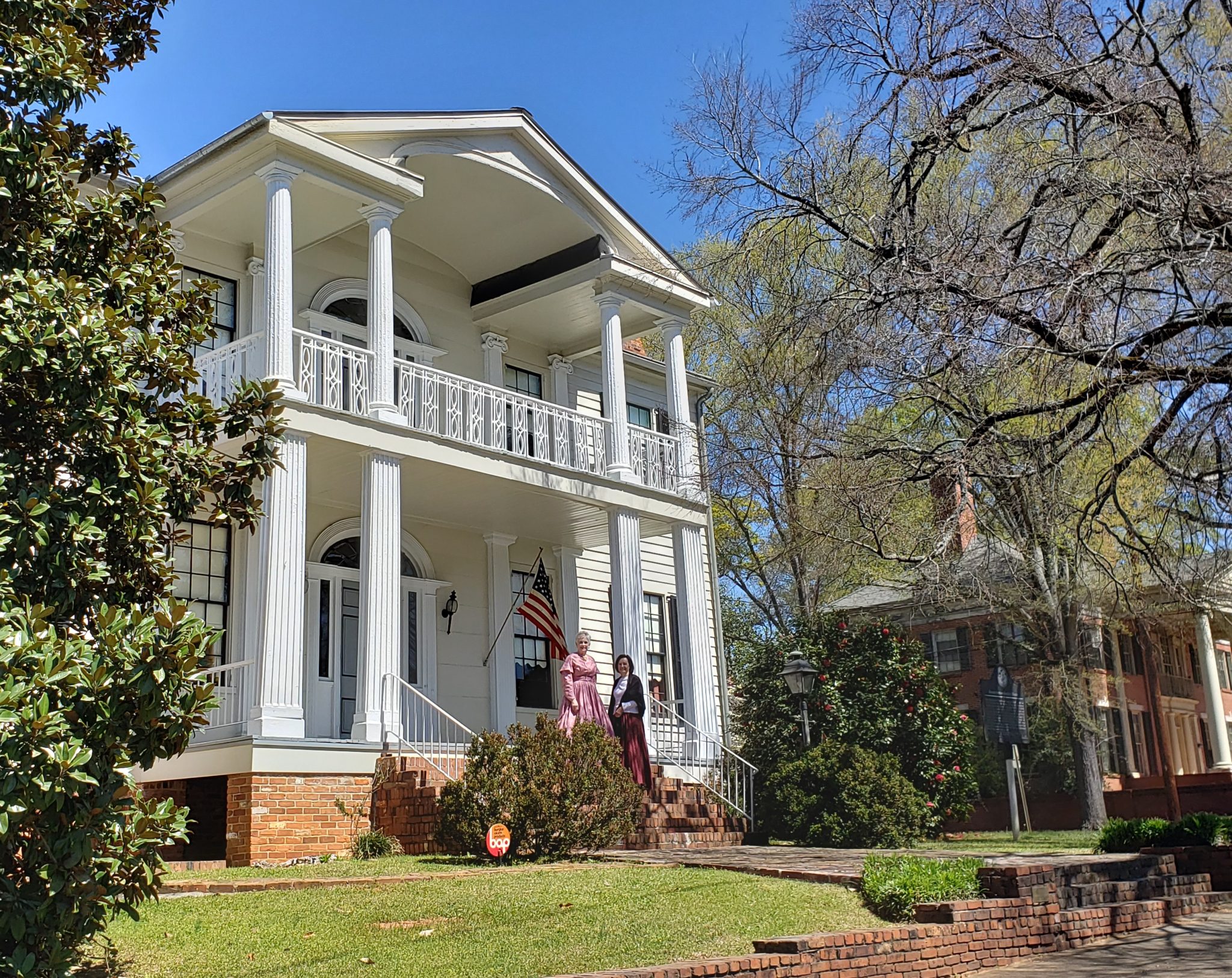 The double-porch white Brown-Stetson-Sanford House with two costumed interpreters near the entrance.