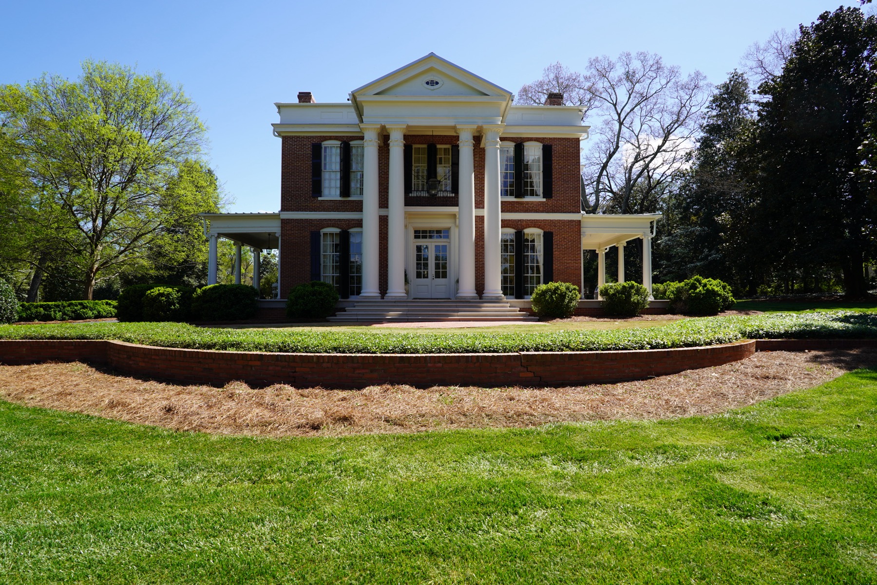 The white two-story McDaniel-Tichenor House behind a broad lawn in Monroe.