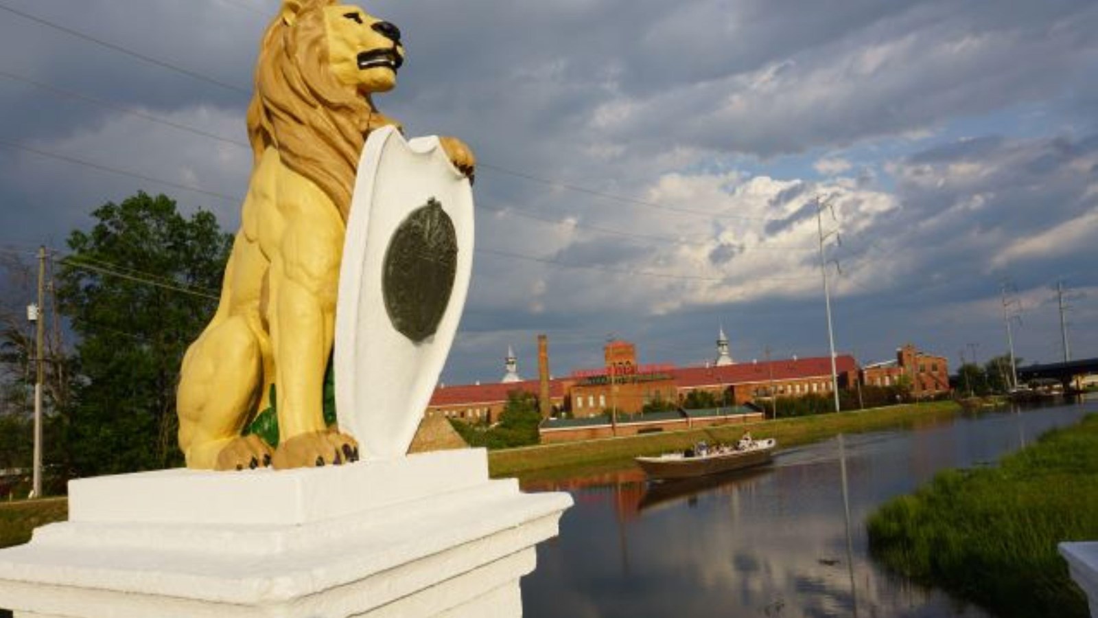 A Petersburg boat on the Augusta Canal beside Enterprise Mill and a bridge lion.