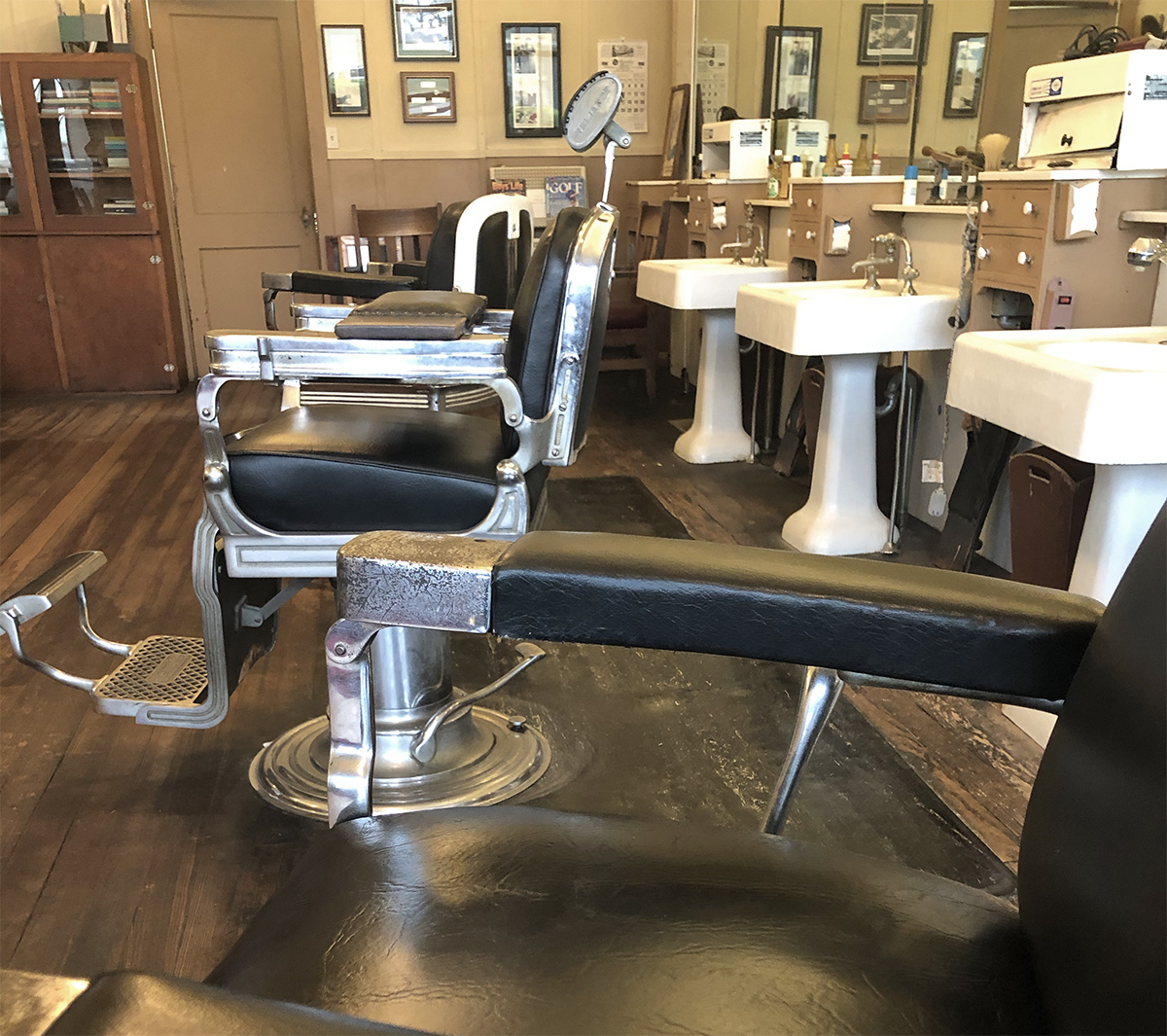 Period barber chairs, mirrors, sinks and tools in the reconstructed Graco barbershop exhibit at the Grady County History Museum.