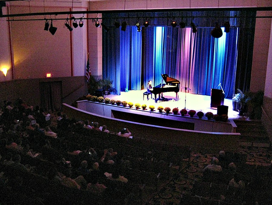 Audience seating and the lit stage inside the Historic Ritz Theatre during a live piano performance.