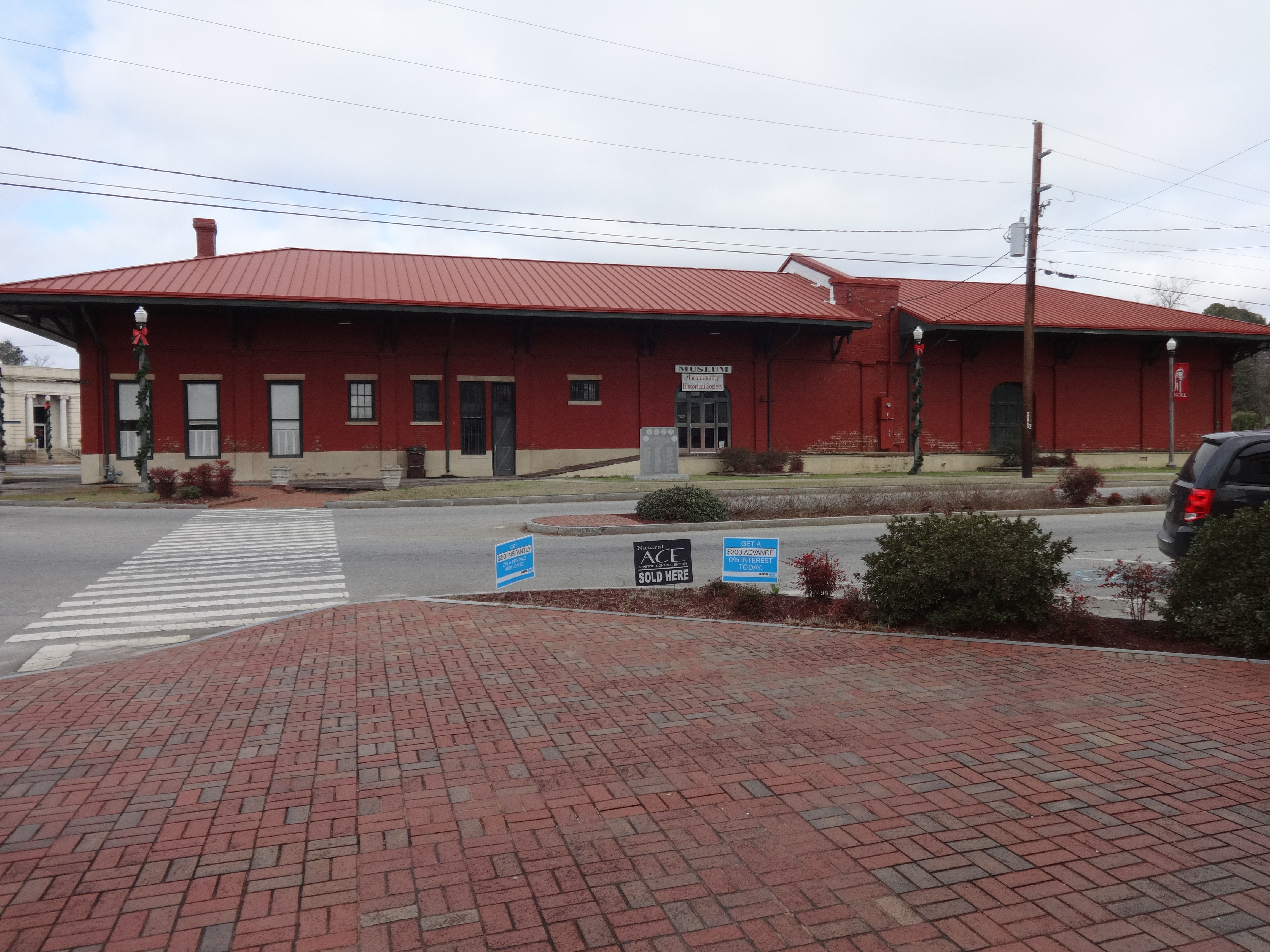 The long red-brick Montezuma depot with a Macon County Historical Society museum sign beside its entrance.