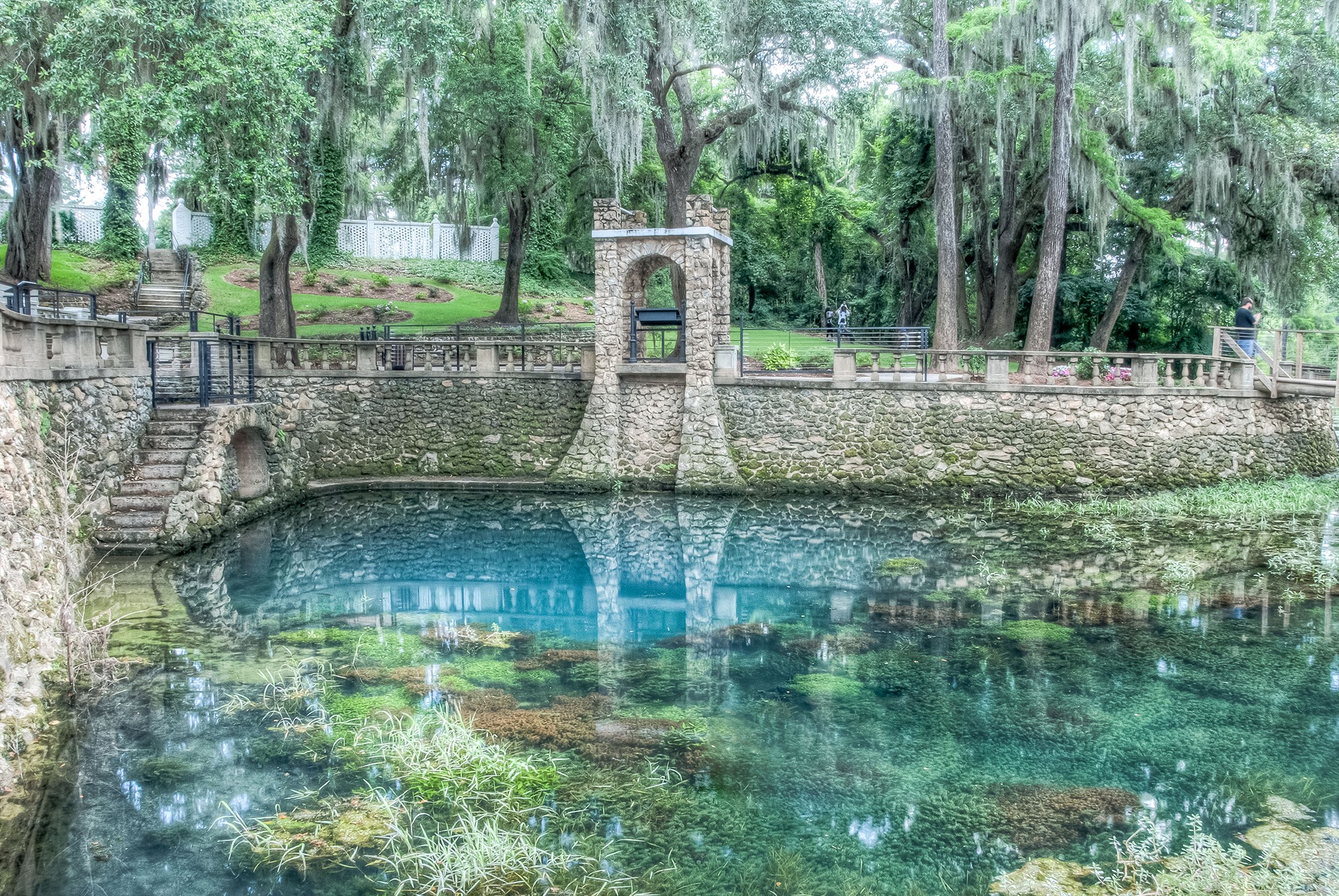 Clear blue water, stone terraces and large moss-draped trees at Radium Springs Gardens.