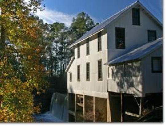 Hamburg State Park's restored gristmill beside its spillway and wooded lake shore.