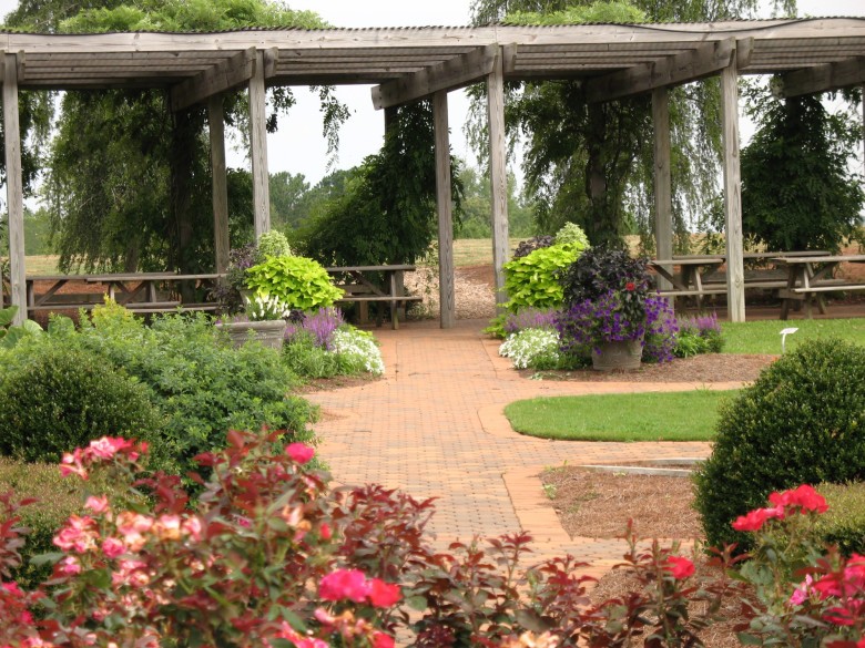 Flower-lined brick garden path leading to a wooden pergola at the UGA Research and Education Garden