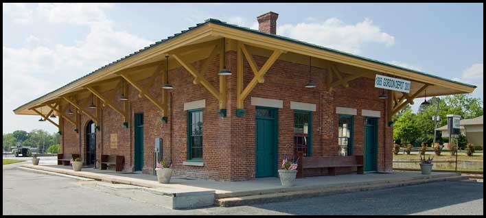 Gordon Depot exterior with the 1885 depot sign and railway beside the building.